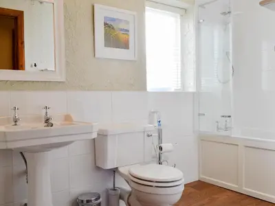 a white bathroom with a toilet and a sink at Rose Patch Cottage in Keswick