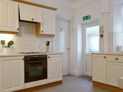 a kitchen with white cabinets and a stove top oven at Skiddaw in Keswick