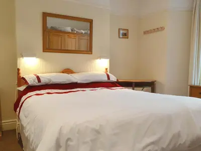 a bedroom with a large white bed with a mirror on the wall at Skiddaw in Keswick