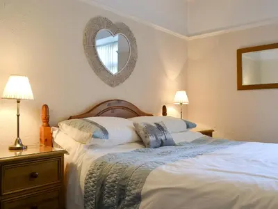 a bedroom with a large bed with a mirror on the wall at Cat Bells in Keswick