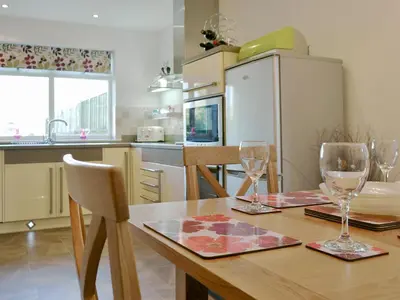 a kitchen with a wooden table with two wine glasses at Cobble Garth in Keswick