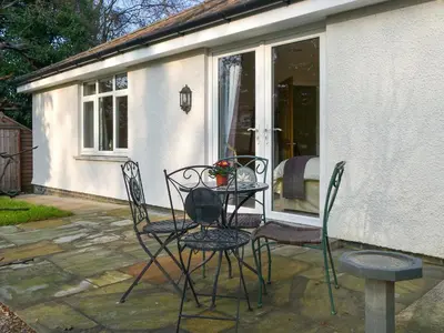 a patio with two chairs and a table with flowers at Cobble Garth in Keswick
