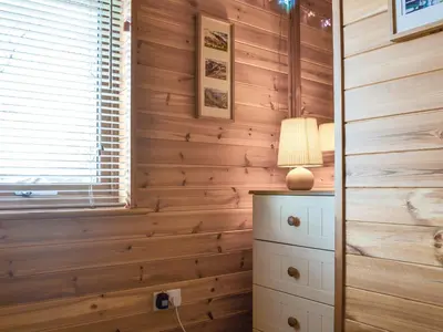 a room with wooden walls and a lamp on a dresser at Larchwood in Ellonby