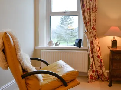 a chair sitting in front of a window with a tree at Hawthorne House in Bassenthwaite Lake