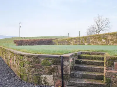a stone retaining wall with a set of stairs at Liftingstane Cottage in Closeburn
