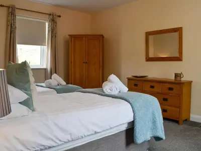 two beds in a bedroom with a mirror and a dresser at Liftingstane Cottage in Closeburn