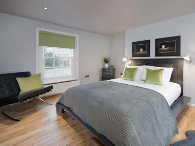 a bedroom with a large bed and a chair at Granary in Gatehouse of Fleet