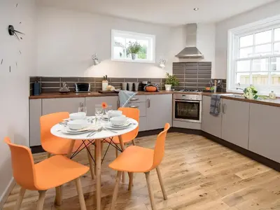a kitchen with a table and orange chairs in a kitchen at Willow in Gatehouse of Fleet