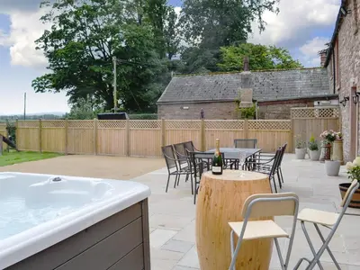 a patio with a tub and tables and chairs at The Wheat Shed in Calthwaite