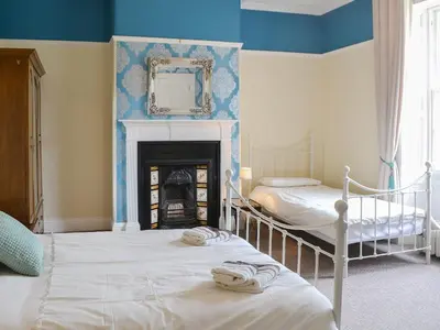 two beds in a room with a fireplace and a mirror at Blaithwaite House in Blencogo