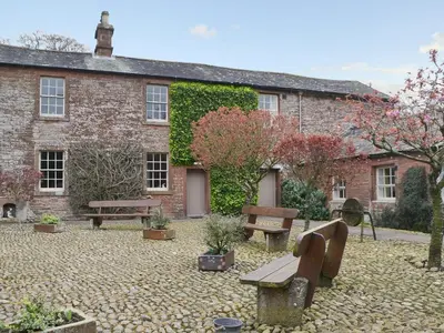 a courtyard with benches and plants in front of a building at Blaithwaite Stables in Blencogo