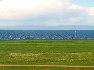 a green field with the ocean in the background at Fairfield House Hotel in Ayr