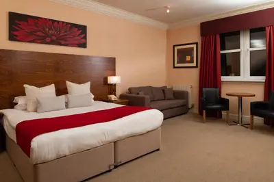 a hotel room with a large bed and a couch at Fairfield House Hotel in Ayr