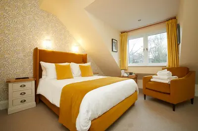 a bedroom with a large bed and a chair at Willowbeck Lodge Boutique Hotel in Carlisle