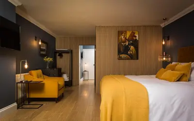 a hotel room with a bed and a yellow chair at Willowbeck Lodge Boutique Hotel in Carlisle
