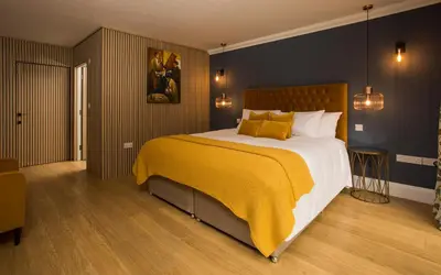 a bedroom with a large bed with a yellow blanket at Willowbeck Lodge Boutique Hotel in Carlisle