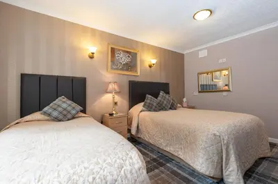 a bedroom with two beds and a lamp on a table at The Hill Hotel in Dumfries