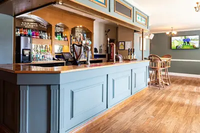 a bar in a pub with a counter and chairs at Lake District Castle Inn Hotel & Spa in Keswick
