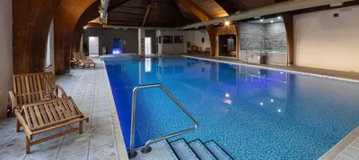 a large swimming pool with a bench and a chair at Lake District Castle Inn Hotel & Spa in Keswick