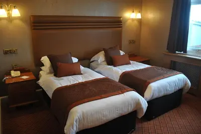 a hotel room with two beds and a window at Cairndale Hotel & Spa in Dumfries