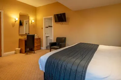 a hotel room with a bed and a desk and a television at Cairndale Hotel & Spa in Dumfries