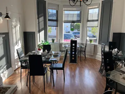 a dining room with tables and chairs and windows at Beechwood Ensuite Guest House in Ayr