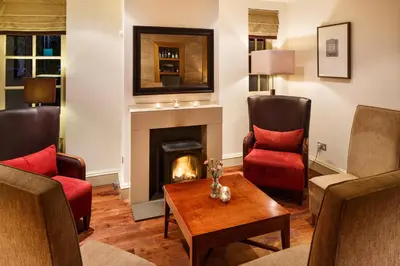 a living room with two chairs and a fireplace at Holiday Inn Dumfries by IHG in Dumfries