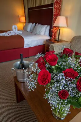 a hotel room with roses on a table with a bed at Holiday Inn Dumfries by IHG in Dumfries