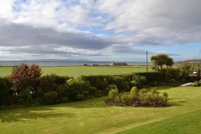 a garden with a view of a field and the ocean at Burnside Farm B & B in Girvan