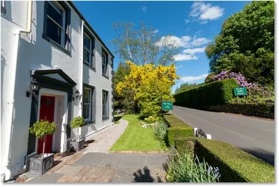 a white house with a red door and a street at Powe House in Keswick
