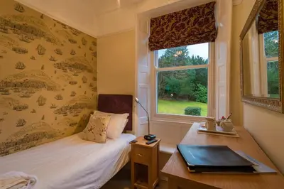 a bedroom with a bed and a desk and a window at Powe House in Keswick