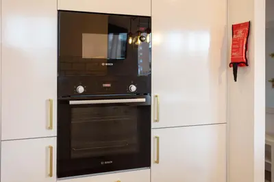 a black microwave in a kitchen with white cabinets at Harbour House - Donnini Apartments in Ayr