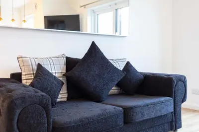 a blue couch with pillows in a living room at Harbour House - Donnini Apartments in Ayr