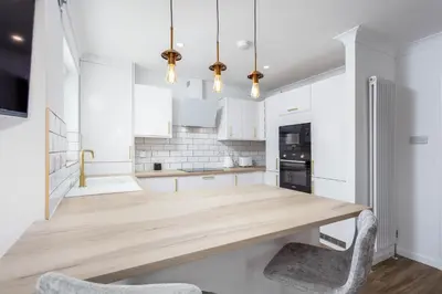 a kitchen with a wooden table and two chairs at Harbour House - Donnini Apartments in Ayr