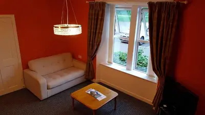 a living room with a chair and a table and a window at Central Dumfries in Dumfries