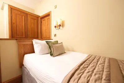a bedroom with a bed with white sheets and green pillows at The Coledale Inn in Keswick