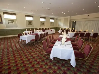 a banquet hall with white tables and red chairs at The Golf Hotel in Silloth