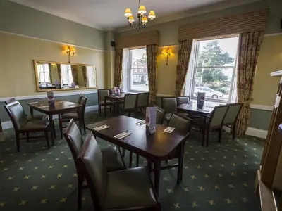 a dining room with tables and chairs and windows at The Golf Hotel in Silloth
