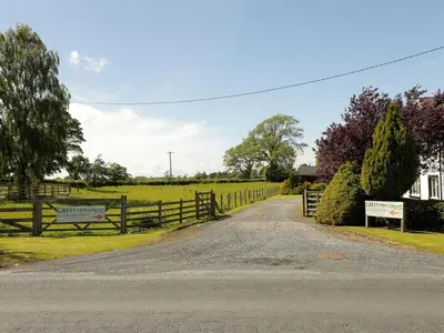 a farm road with a fence and a field at Green View Lodges in Wigton