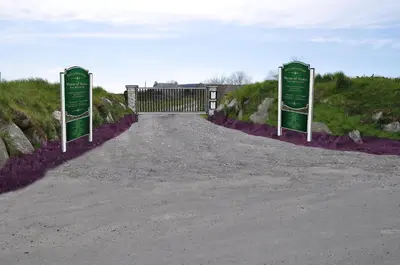 a gate with two green signs on the side of a road at The Barn at Ballaloaghtan in Ballasalla