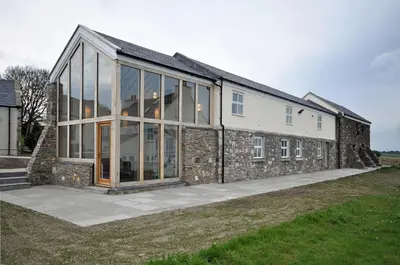 a stone house with large glass windows on the side of it at The Barn at Ballaloaghtan in Ballasalla