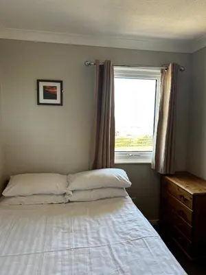 a bedroom with a bed and a window at Burrowhead Holiday Village in Isle of Whithorn