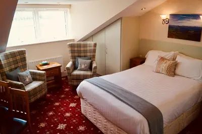 a hotel room with a bed and two chairs at Old Posting House in Cockermouth