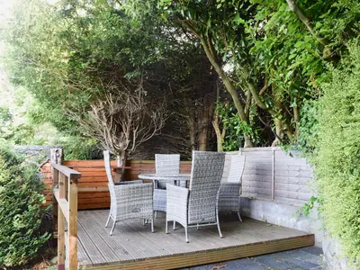 a table and chairs on a wooden deck with trees at Brandelhow in Keswick