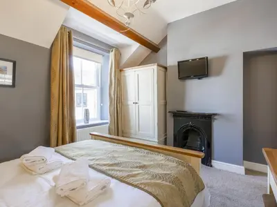 a bedroom with a bed with a fireplace and a television at Tommy's Cottage in Keswick