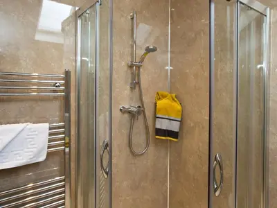 a shower with a glass door and a yellow towel at Elmcot in Keswick