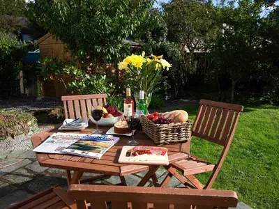 a picnic table with a basket of fruit and wine bottles at Elmcot in Keswick