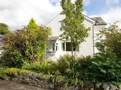 a white house with trees and plants in front of it at Elmcot in Keswick