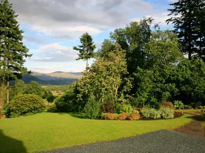a garden with green grass and trees and mountains at Carrigbaun in Braithwaite