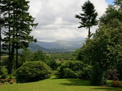 a green field with trees and mountains in the distance at Carrigbaun in Braithwaite
